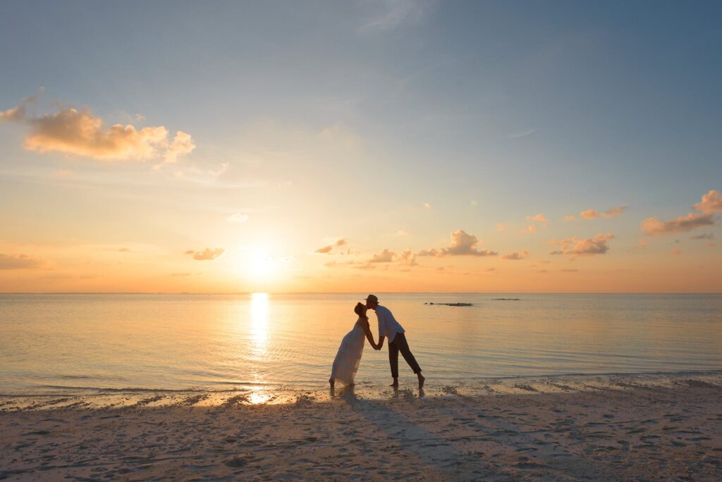 man and woman standing on shore kissing after a micro wedding