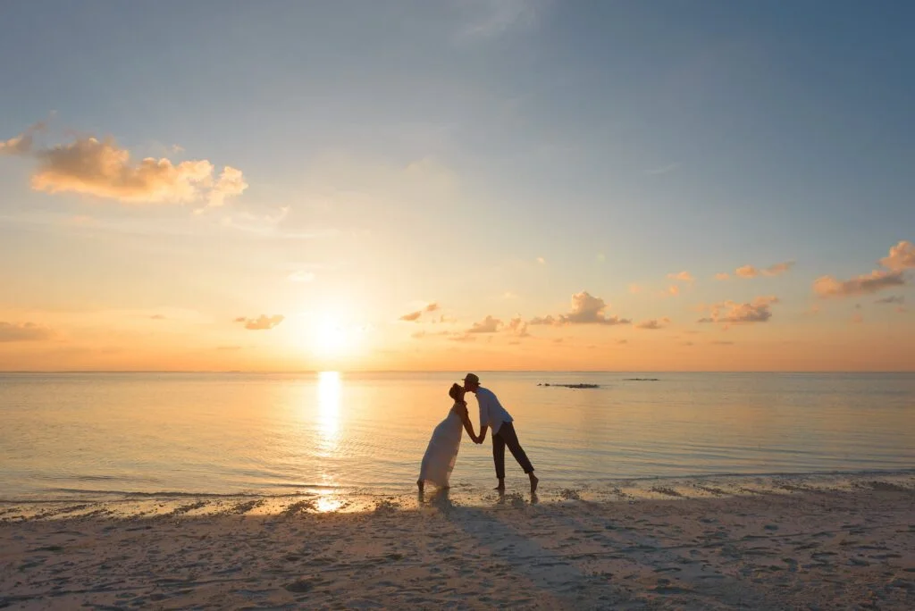 man and woman standing on shore kissing after a micro wedding