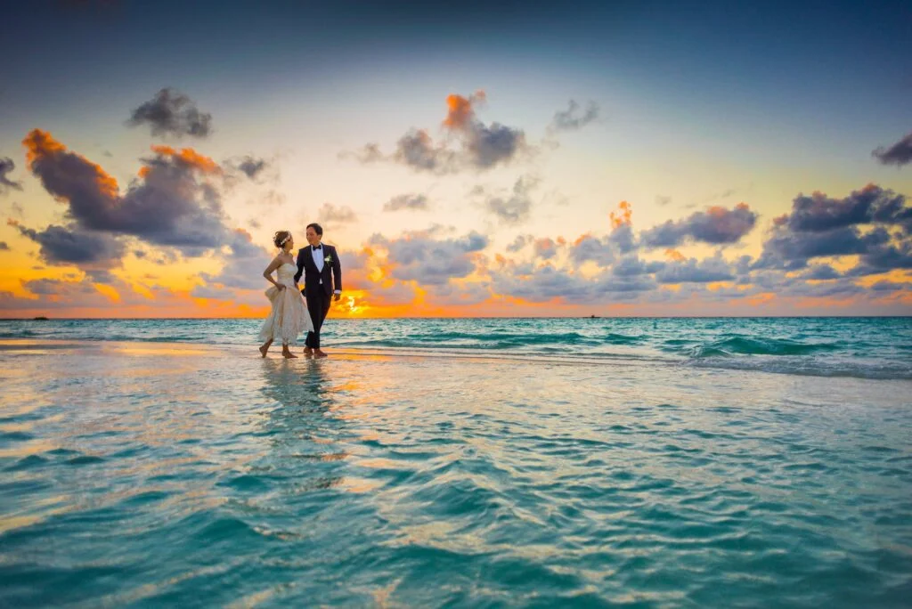 bride and groom walking on a beach near the water