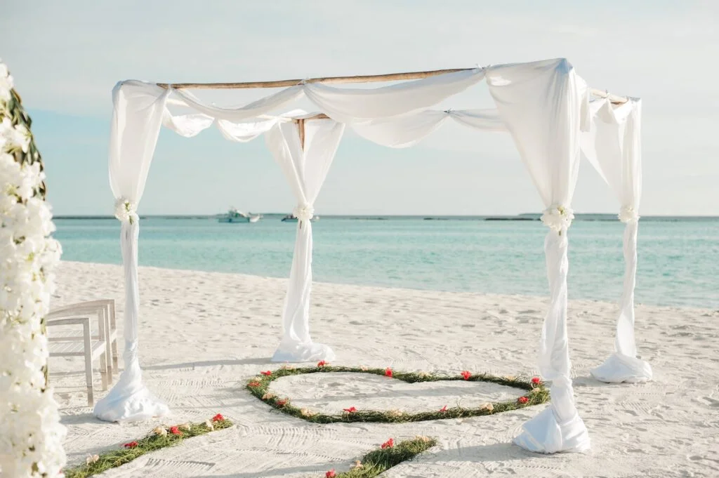 white fabric canopy tent with green heart floor decor at beach
