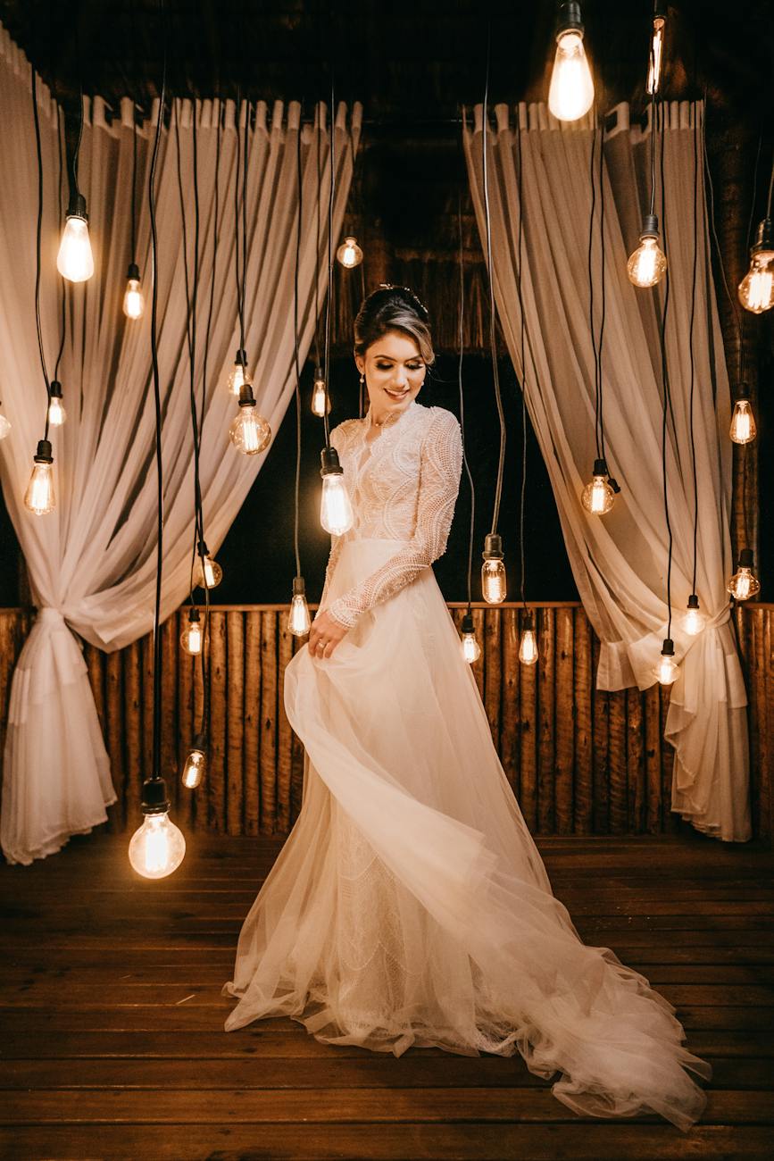 woman standing beside hanging light bulbs in a bridal gown dancing at a micro wedding