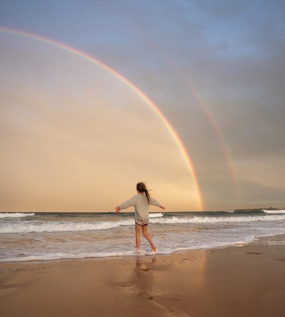 woman on surfside beach with rainbow who is happy because she bought travel insurance for her texas beach house